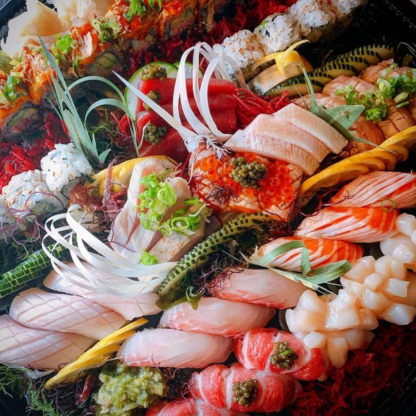 A large platter of assorted Soho Japanese Restaurant sushi, sashimi, and rolls, garnished with caviar and scallions.