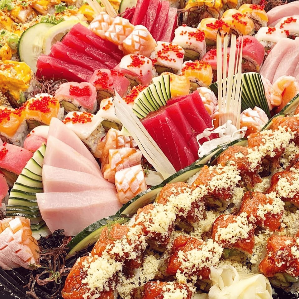 A large platter of colorful Soho Japanese Restaurant sushi and sashimi, garnished with cucumber and lemon.