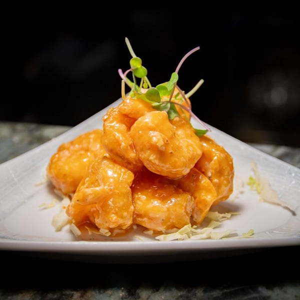 Soho Japanese Restaurant's crispy shrimp appetizer, coated in a creamy orange sauce and garnished with microgreens.