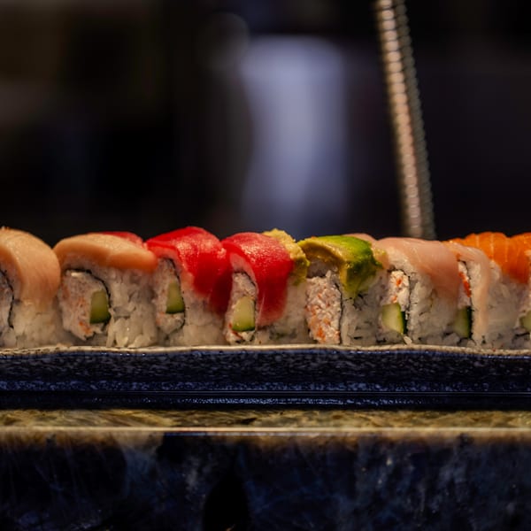 A row of colorful sushi rolls with various toppings, including tuna, salmon, and avocado.