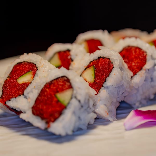 Close-up of Soho Japanese Restaurant's spicy tuna sushi rolls with cucumber and a pink orchid petal.
