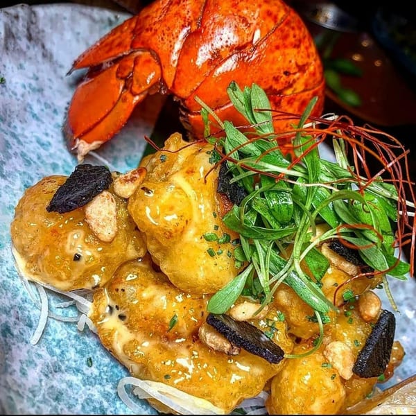 Soho Japanese Restaurant's crispy rock shrimp tempura with a bright orange lobster tail in the background.