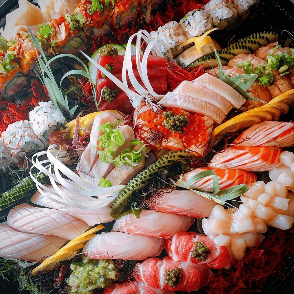 A vibrant platter of assorted Japanese sushi and sashimi, garnished with roe, scallions, and seaweed.